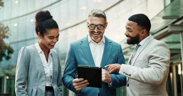 Trois collègues consultant ensemble une tablette dans un bureau